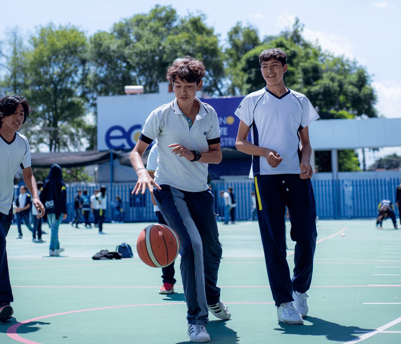 Dos alumnos con uniforme deportivo juegan básquetbol en la cancha del colegio