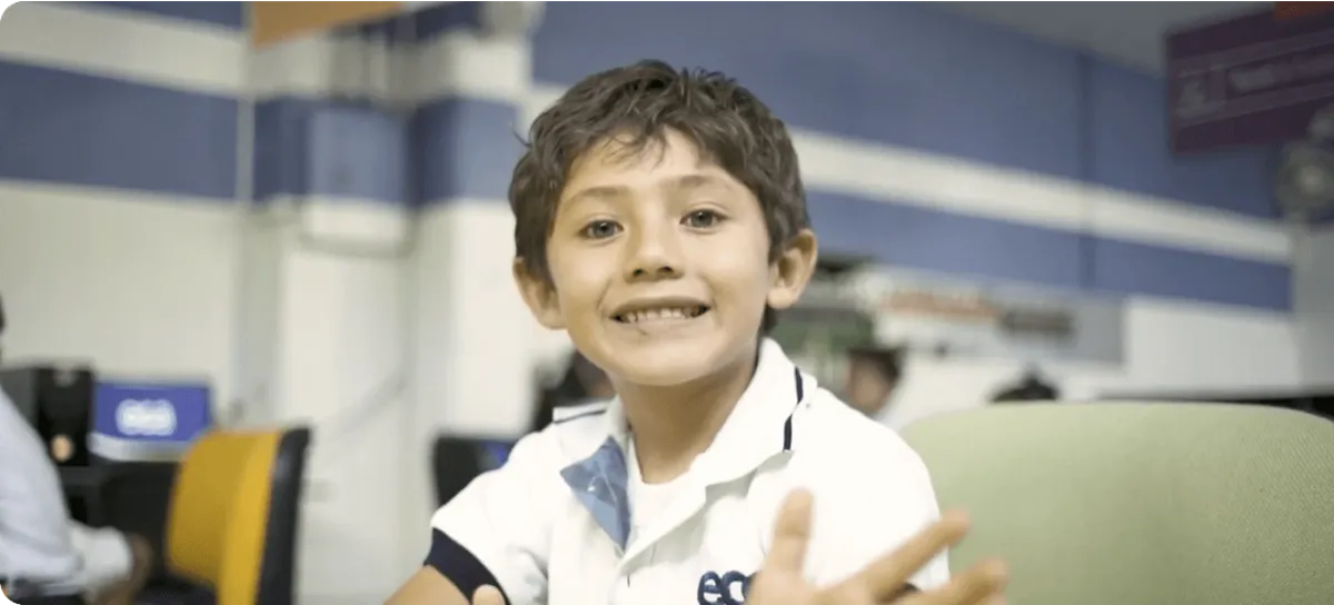 Niño sonriente con playera blanca y el logotipo ECA habla frente a la cámara